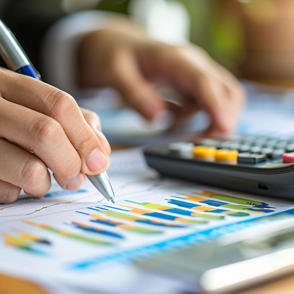 a person using a scientific calculator while using a pen to write on a bar chart on a sheet of paper