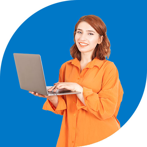 a ginger woman in a orange shirt holding a laptop and smiling towards the viewer