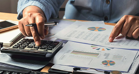 a bookkeeper using a calculator and looking through papers of revenue